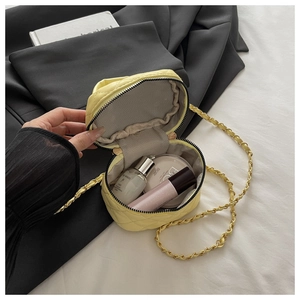 Detail view of yellow quilted chain bag interior with herringbone lining and cosmetics