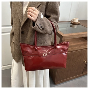 Detail of burgundy glossy tote bag with a fine strap and elegant golden metal buckle
