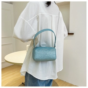 Détail du sac cylindrique à paillettes bleu clair avec bandoulière en chaîne métallique