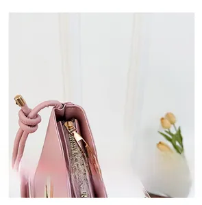 Detail of pink PU bucket bag featuring a smooth metal zipper and unique knotted strap