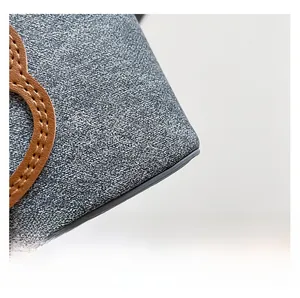 Macro detail of textured fabric and brown leather applique with fine white stitching
