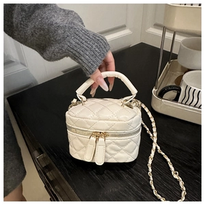 Close-up of beige quilted mini box bag with gold chain strap and dual zipper detail