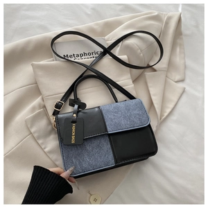 Detail of checkered denim and black leather crossbody bag on a beige blazer background