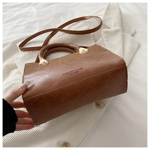 Detail of vintage brown leather handbag with woven handle and gold hardware