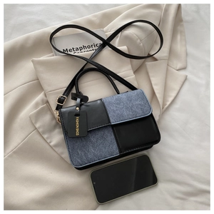 Detail of mini square bag featuring black leather, grey denim patchwork and gold metal hardware