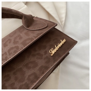 Gros plan sur la texture léopard et le logo doré de ce sac à main rétro marron