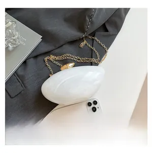 Detailed top view of white marble acrylic shell clutch bag with gold chain strap