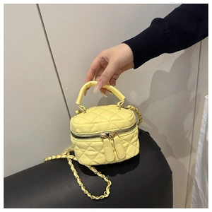 Detailed close-up of yellow quilted mini bucket bag with gold chain strap and handles