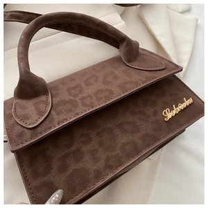 Détail du sac à main marron imprimé léopard avec un élégant logo doré en métal