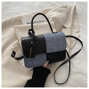 Close-up of black leather and blue denim patchwork small square bag with fashion tag