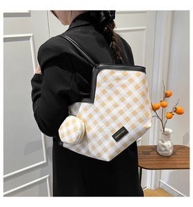 Close-up of a yellow checkered tote bag with a matching mini pouch worn by a model
