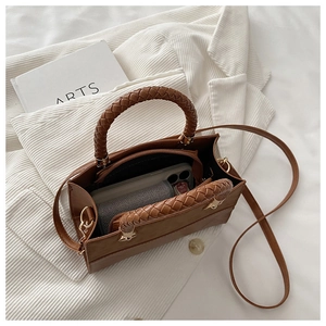 Detailed macro view of the brown leather handbag with a unique spiral woven handle detail