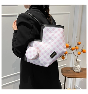 Detail of pink plaid heart-shaped tote bag with accessory and branded black logo patch