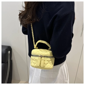 Close-up of yellow quilted leather vanity bag with gold chain strap and top handle