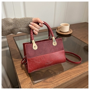 Detail of red leather handbag showing mixed textures and woven handle in lifestyle setting