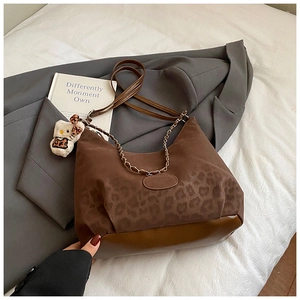 Detail of leopard print suede shoulder bag with gold chain strap and plush charm