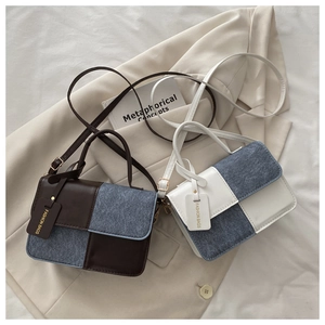 Detail view of two-tone faux leather and denim crossbody bags with elegant metal hardware