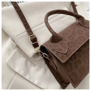 Détail du sac à main brun foncé à texture animale avec boucle dorée et anse