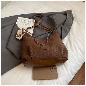 Detailed close-up of brown leopard print bag with gold chain and plush cat charm accessory