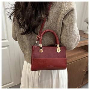 Detail of burgundy patchwork crossbody bag showing suede texture and braided handle