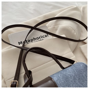 Detail of blue textured flap and brown leather crossbody bag on a white coat