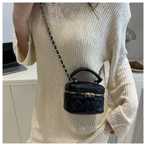 On-body shot of a quilted black leather mini vanity bag with a woven metal chain strap