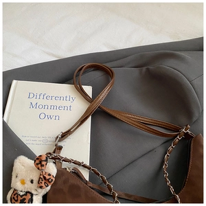 Close-up of a brown shoulder bag with a metal chain and a cute leopard plush charm