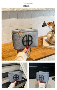 Detail of blue denim square bag featuring metallic chain and circular logo on wooden table
