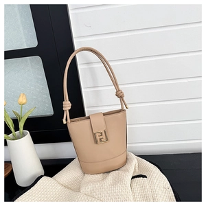Detail of beige leather bucket bag with gold geometric hardware and knotted strap handles