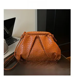 Detail of orange woven cloud bag with intricate puffy texture and leather shoulder strap