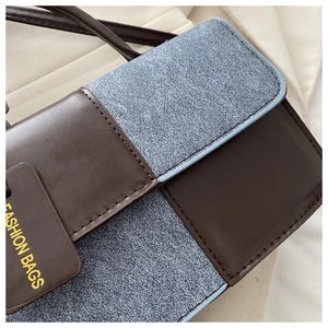 Detail of color-block shoulder bag with brown leather and blue denim fabric textures