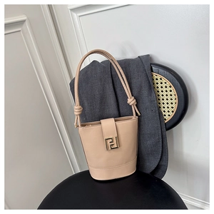 Detail of elegant beige bucket bag with gold square buckle on a black chair