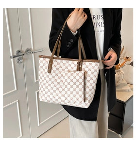 Detail of the chic beige tote bag showing the textured brand pattern and leather strap