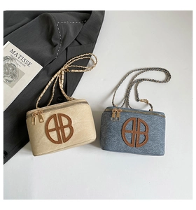 Detail of canvas box bags with circular leather logo and chain straps in beige and blue