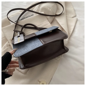 Detail of vintage crossbody bag showing contrast leather and fabric texture with gold hardware