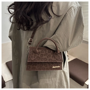 Détail d'un sac à main léopard marron avec logo doré porté sur un manteau beige élégant