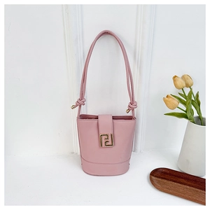 Pink bucket bag with golden geometric clasp and knotted shoulder strap on minimalist white base
