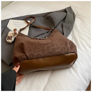 Detail of leopard print shoulder bag with brown leather trim and metal chain accents