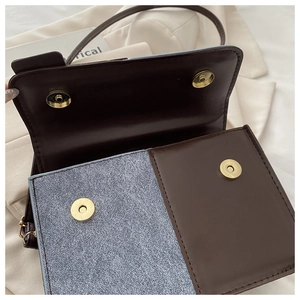 Detail of crossbody bag flap featuring dual magnetic snap buttons and textured fabric contrast