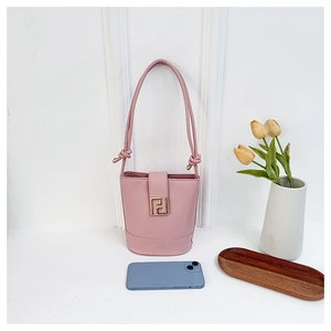 Pink matte leather bucket bag detail with gold metal buckle and smartphone for scale