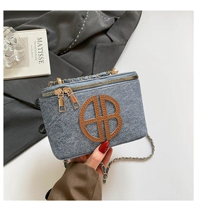 Detailed close-up of grey tweed crossbody bag with brown leather logo and gold chain