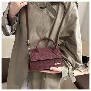 Détail du sac bandoulière bordeaux avec gaufrage léopard et logo en métal doré