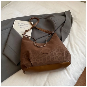 Detail of leopard print stitching and smooth brown leather on crossbody bag with chain strap
