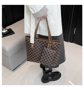 Detail of checkered leather tote bag with small charm pouch held by a model