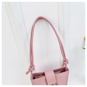 Detail of pink leather handbag showing elegant knot handle and gold metal buckle hardware