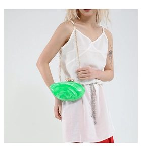 Detail view of emerald green marble clutch with gold chain strap on model shoulder