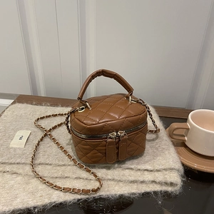 Brown quilted mini bucket bag with chain strap and gold hardware on cozy wool background