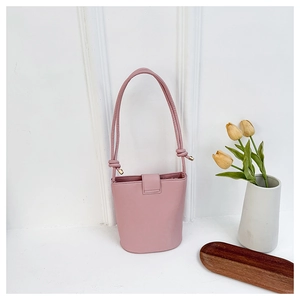 Detail of pink PU leather bucket bag with knotted straps and buckle on white background