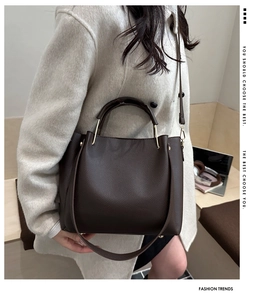 Borsa tote marrone scuro con trama litchi indossata da una modella con cappotto beige