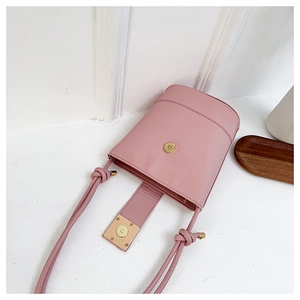 Detailed view of pink bucket bag featuring a gold magnetic clasp and decorative knotted strap